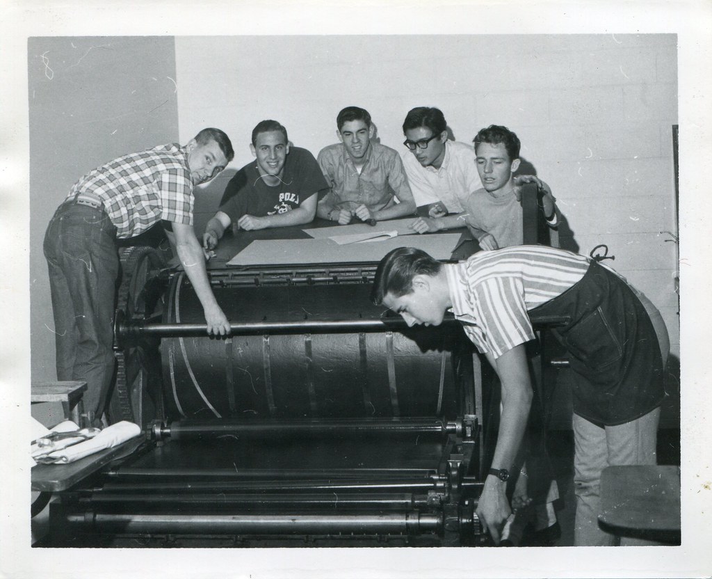 Six male students posing around a vintage press machine.