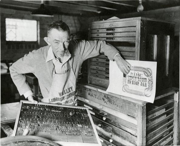 Charles Palmer leaning against drawers of stamps.