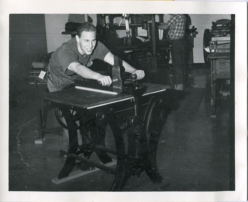 Young man using the paper cutter.
